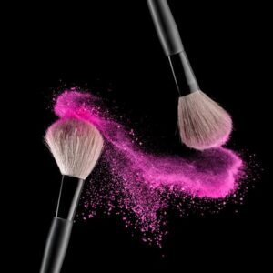 two make up brushes with pink powder falling from them